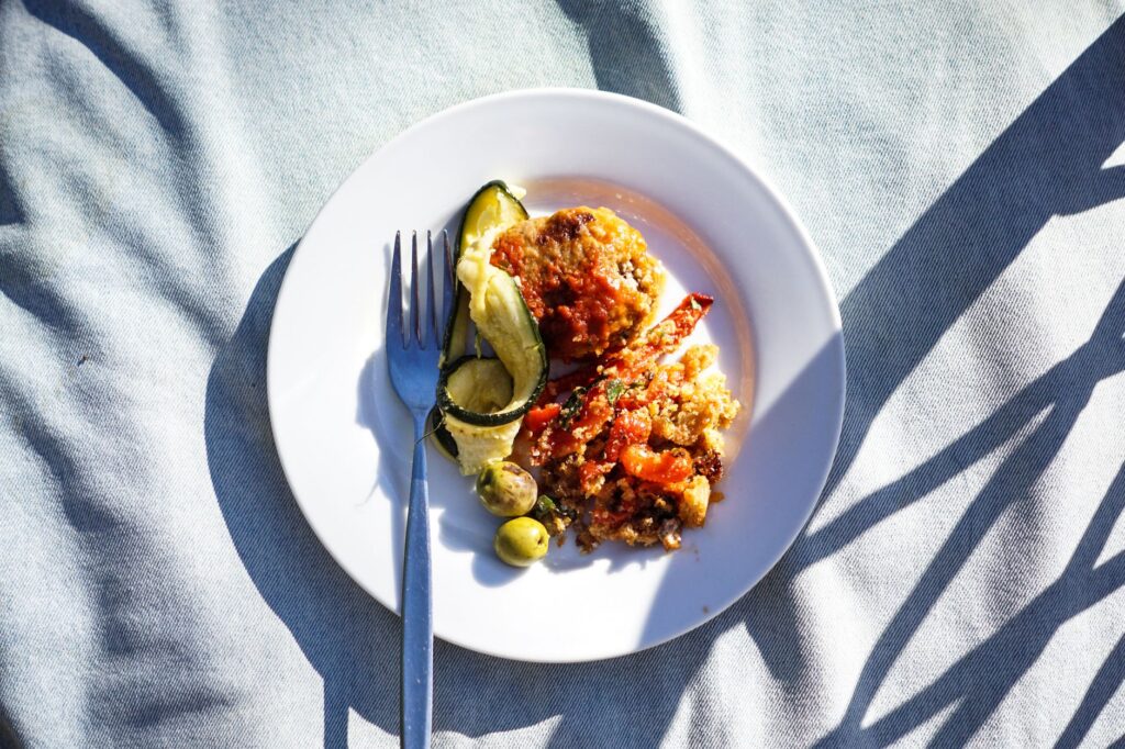 Un repas vibrant de quinoa et de légumes servi sur une assiette blanche avec une fourchette et des ombres.