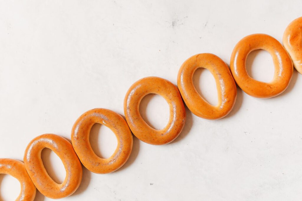 Des bagels ronds fraîchement cuits, disposés en diagonale sur une surface blanche.