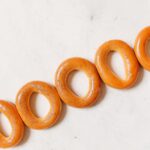 Des bagels ronds fraîchement cuits, disposés en diagonale sur une surface blanche.