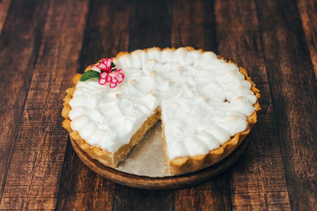 Gros plan sur une délicieuse tarte crémeuse avec décoration florale sur du bois.