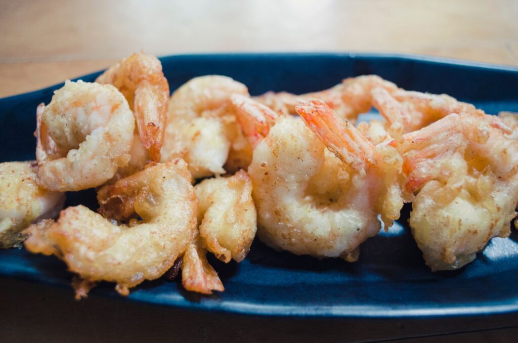 Gros plan tentant de crevettes frites croustillantes servies dans une assiette bleue, parfait pour les amateurs de fruits de mer.