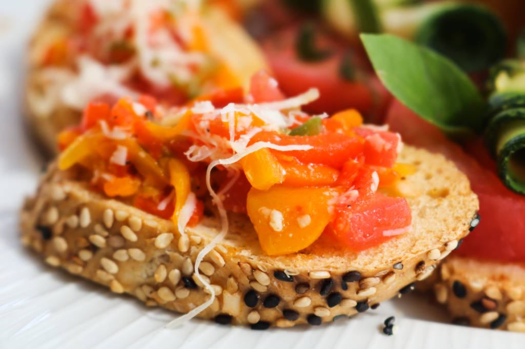 Gros plan de bruschetta colorée garnie de légumes frais et de fromage, mettant en avant une collation délicieuse et saine.