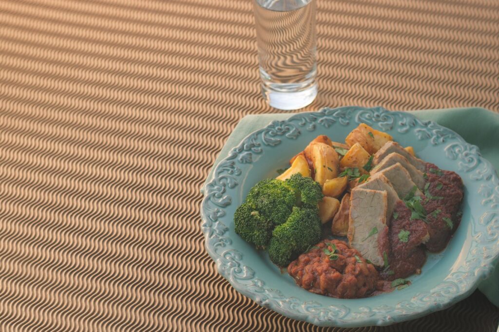 Un plat magnifiquement présenté avec de la viande tranchée, des brocolis et des pommes de terre sur une assiette ornée.