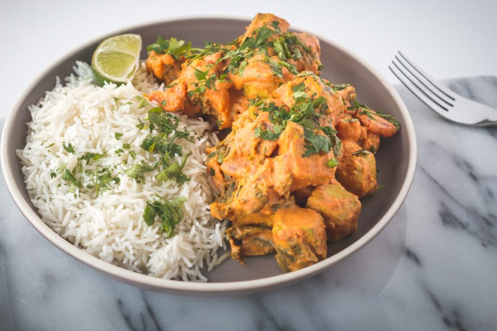 Un curry indien savoureux servi avec du riz jasmin et garni d'herbes fraîches.