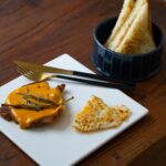 Un petit-déjeuner savoureux avec un œuf au plat, de la viande recouverte de fromage et du pain toasté sur une table en bois.
