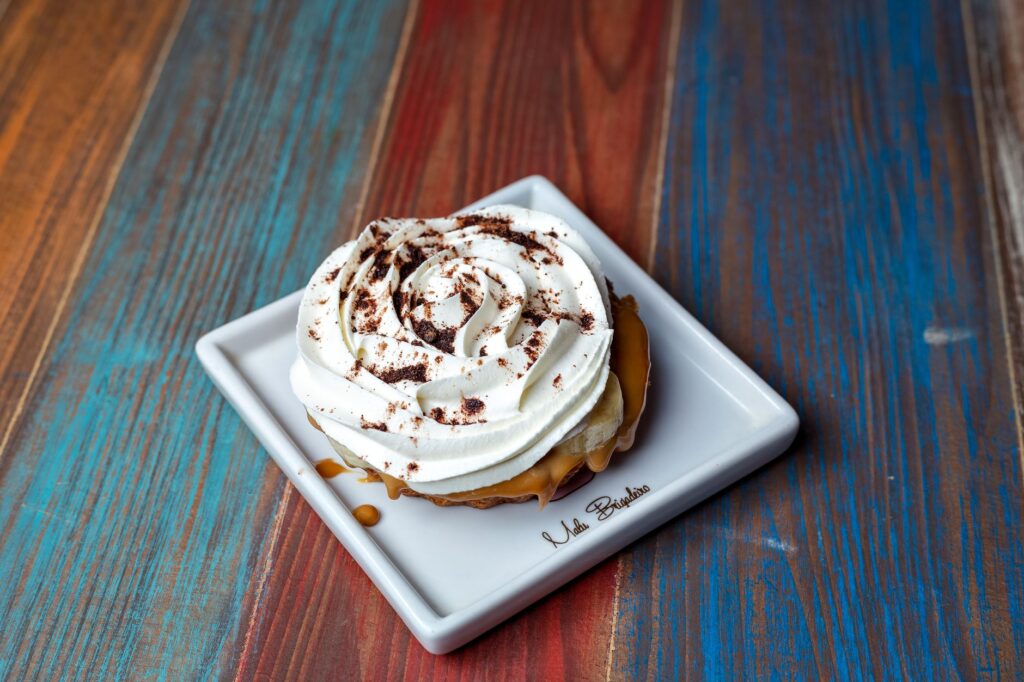 Gros plan sur une tarte banoffee crémeuse avec caramel et glaçage sur une assiette en céramique.