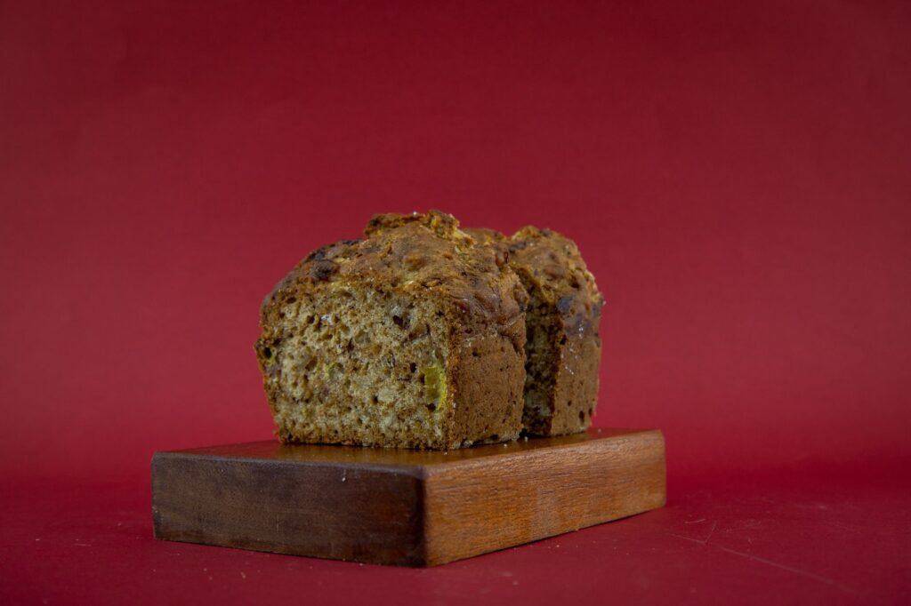Un délicieux pain aux carottes fait maison sur une planche en bois contre un fond rouge.