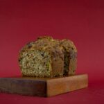 Un délicieux pain aux carottes fait maison sur une planche en bois contre un fond rouge.