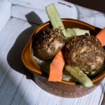 Boules de viande savoureuses maison avec des tranches de concombre et de carotte dans un bol rustique.