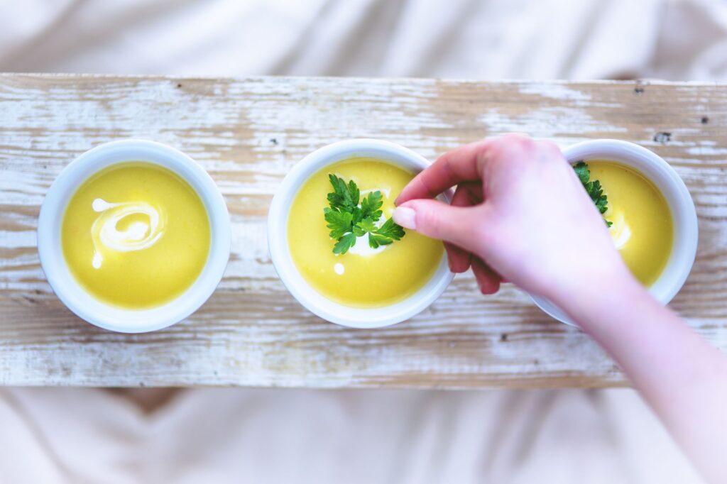Main ajoutant une garniture à des bols de soupe crémeuse, parfaits pour le déjeuner ou le dîner.