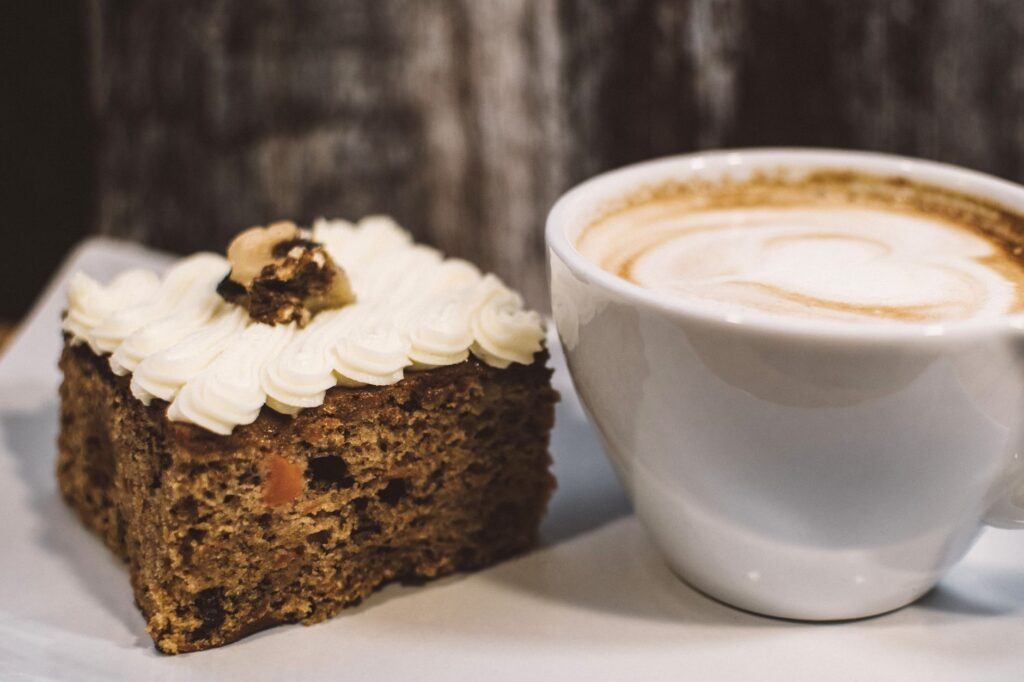 Gros plan captivant d'un cappuccino crémeux accompagné d'une délicieuse part de gâteau.
