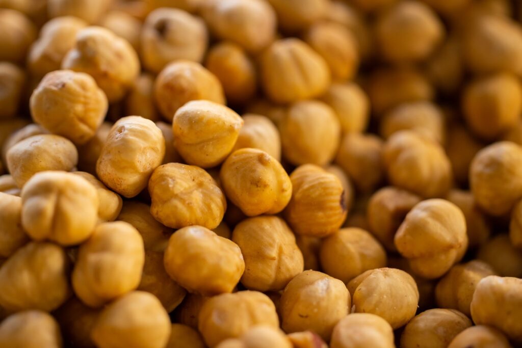Un gros plan de nombreux pois chiches rôtis mettant en valeur leur texture et leur couleur dorée.