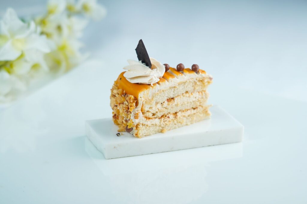 Délicieuse part de gâteau avec un nappage caramel, des noix et un accent chocolat sur une assiette blanche.