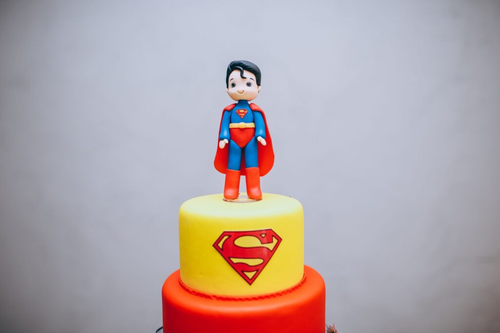 Gâteau de super-héros coloré avec une figurine en pâte à sucre de Superman sur le dessus, parfait pour les fêtes à thème.