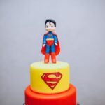 Gâteau de super-héros coloré avec une figurine en pâte à sucre de Superman sur le dessus, parfait pour les fêtes à thème.