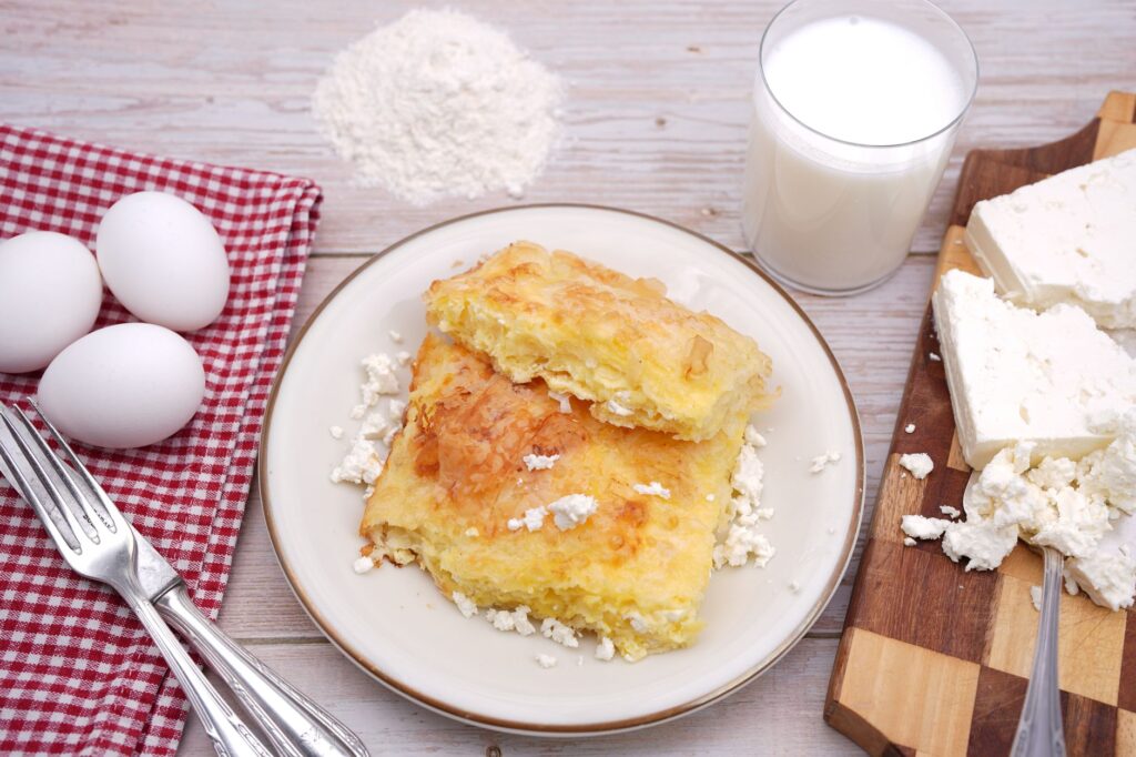 Délicieuse pâtisserie maison servie avec du fromage cottage, des œufs et du lait sur une table en bois.