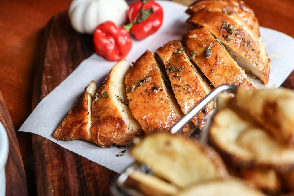 Filet de poulet savoureux tranché avec des herbes, joliment présenté sur une planche en bois pour un attrait culinaire.