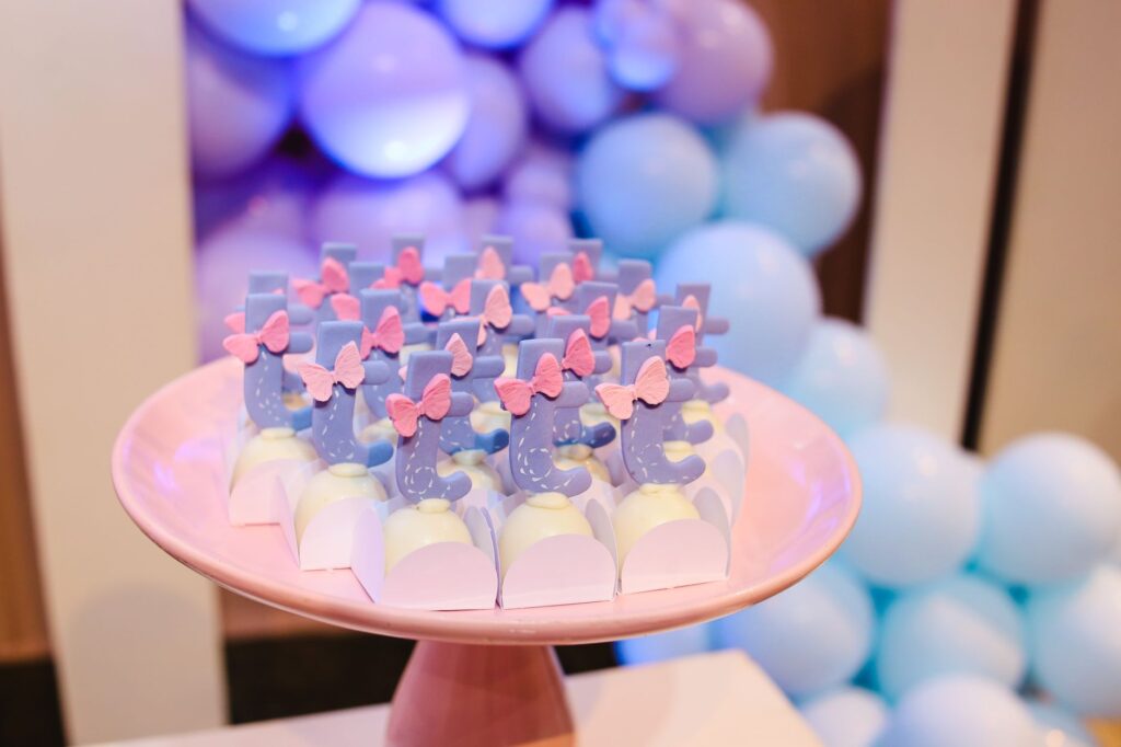 Desserts colorés sur le thème pastel avec des nœuds roses sur un présentoir à gâteaux, parfaits pour les célébrations.