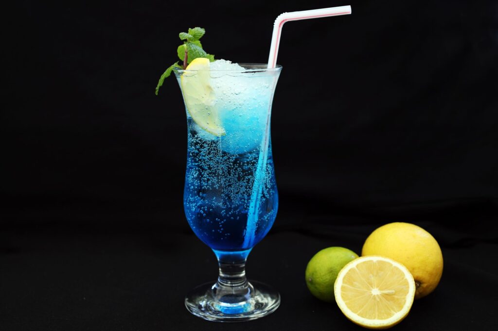 Un cocktail bleu vibrant avec un garniture de citron et de lime sur un fond noir, parfait pour la fraîcheur.