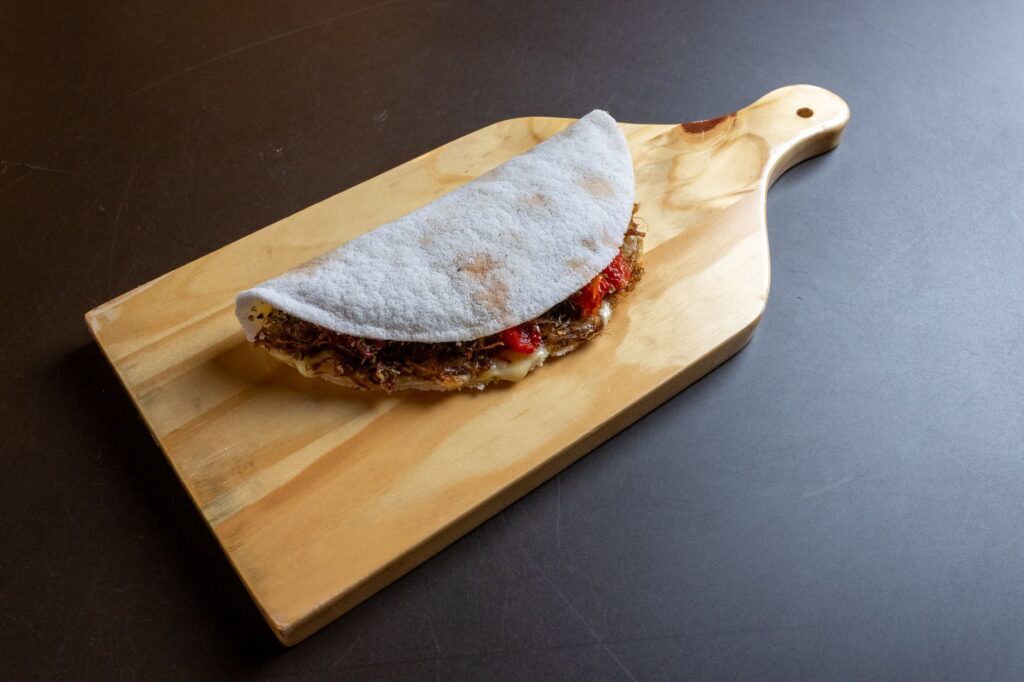 Un wrap de tapioca savoureux rempli d'ingrédients présenté sur une planche en bois.