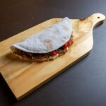 Un wrap de tapioca savoureux rempli d'ingrédients présenté sur une planche en bois.