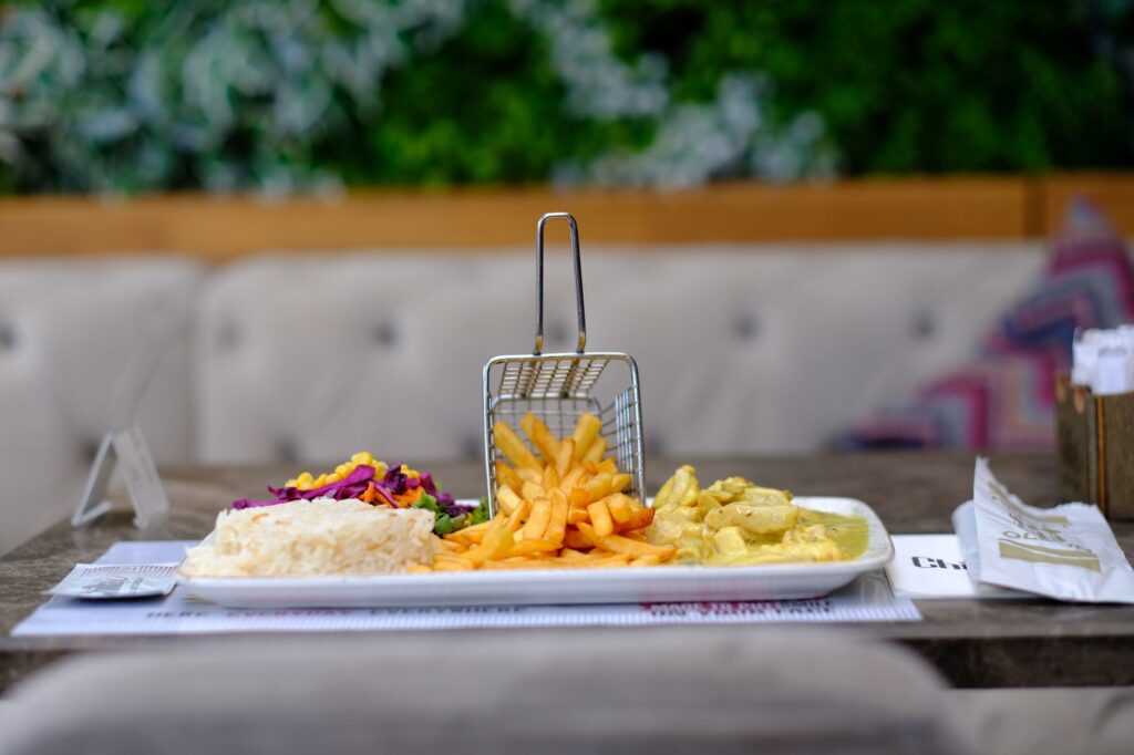 Assiette appétissante avec du poulet au curry, des frites et du riz servie à l'intérieur d'un restaurant.