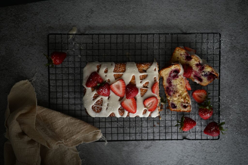 Gâteau délicieux garni de fraises et de glaçage sur une grille de refroidissement.
