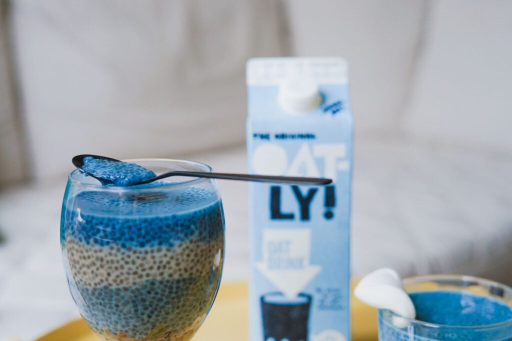 Délicieux pudding de chia bleu servi dans un verre avec du lait d'avoine pour un en-cas beau et sain.