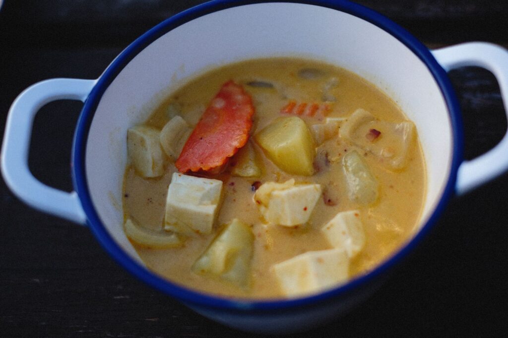 Délicieuse soupe maison de tofu et légumes servie dans un pot blanc rustique.