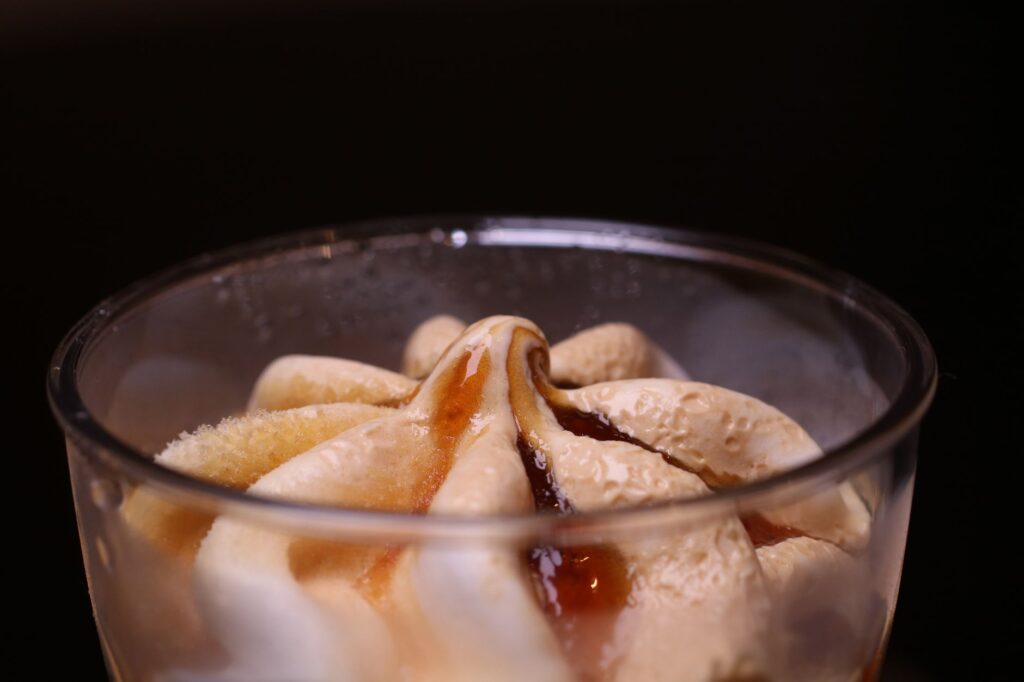 Gros plan sur un délicieux dessert glacé garni de sirop de caramel dans un verre.