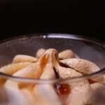 Gros plan sur un délicieux dessert glacé garni de sirop de caramel dans un verre.