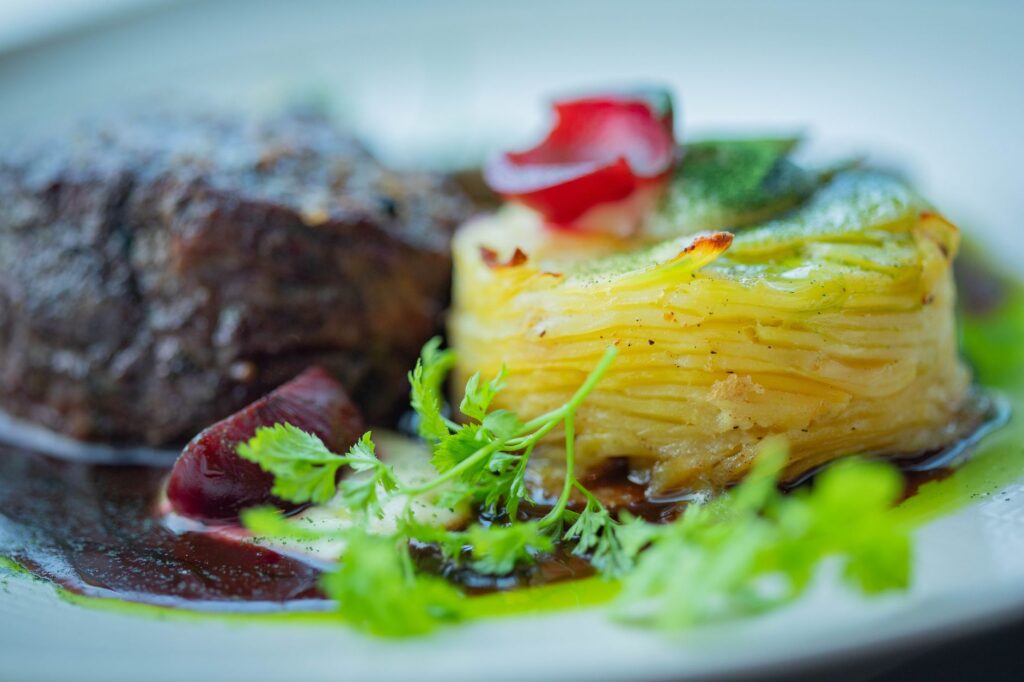 Délicieux repas gourmet avec filet mignon et gratin de pommes de terre aux herbes, parfait pour un dîner raffiné.