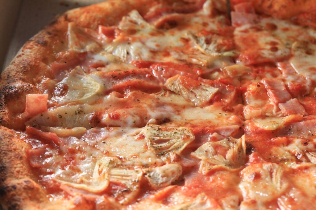 Image attrayante en gros plan d'une délicieuse part de pizza aux artichauts et au fromage, parfaite pour la photographie culinaire.