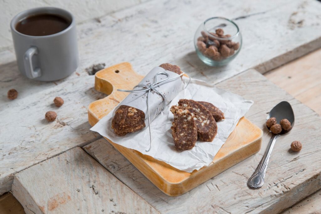 Présentation délicieuse de salami au chocolat aux noix avec café sur une planche en bois rustique. Idéal pour la photographie gastronomique.