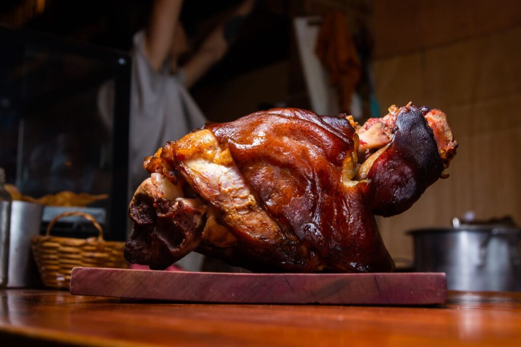 Gros plan d'un jarret de porc rôti croustillant sur une planche à découper en bois, parfait pour des images de stock.