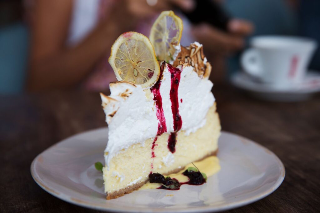 Une délicieuse part de cheesecake au citron meringué surmontée de sirop sucré, capturée dans un cadre accueillant.