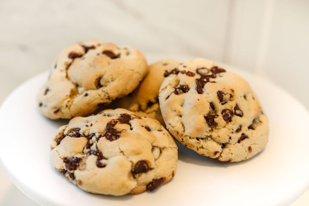 Gros plan de biscuits aux pépites de chocolat fraîchement cuits sur une assiette blanche, mettant en valeur des morceaux de chocolat fondus.