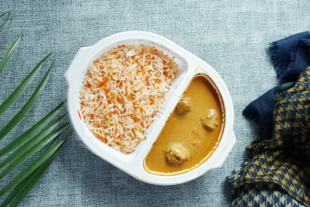Vue aérienne d'un curry savoureux et de riz dans un plat divisé, avec une décoration de table élégante.