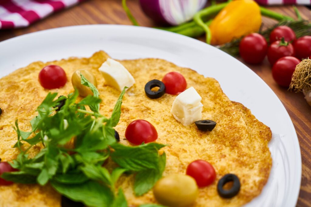 Délicieuse et vibrante omelette garnie de tomates fraîches, d'olives et de fromage sur une assiette.