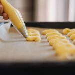 Un gros plan de pâte étant pipée sur du papier sulfurisé, mettant en avant l'art de la pâtisserie.