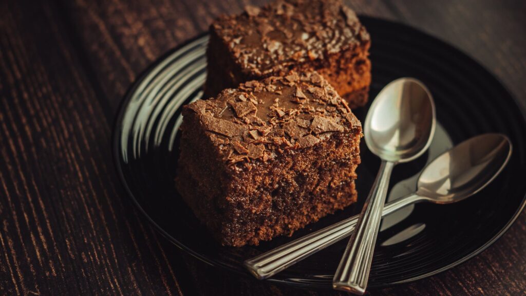 Délicieuses brownies au chocolat faits maison servies sur une assiette noire avec des cuillères.