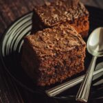 Délicieuses brownies au chocolat faits maison servies sur une assiette noire avec des cuillères.