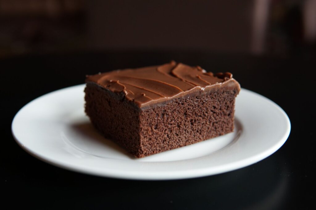 Gros plan d'une tranche de brownie au chocolat sur une assiette blanche, parfait pour les amoureux des desserts.