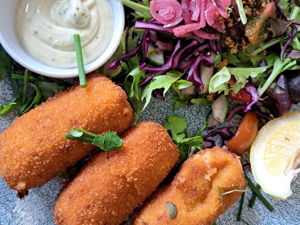 Savourez des croquettes de poisson croustillantes associées à une salade vibrante et une sauce acidulée.