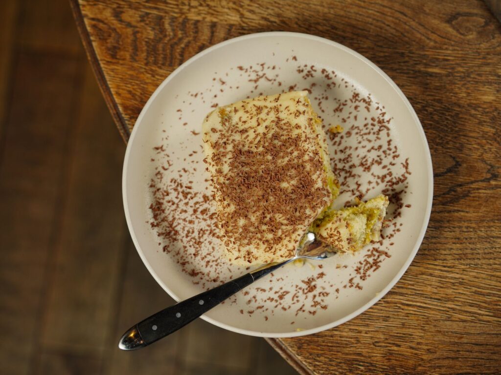 Vue du dessus d'une délicieuse part de tiramisu avec des vermicelles en chocolat sur une assiette.