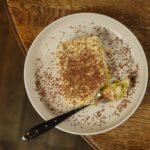 Vue du dessus d'une délicieuse part de tiramisu avec des vermicelles en chocolat sur une assiette.