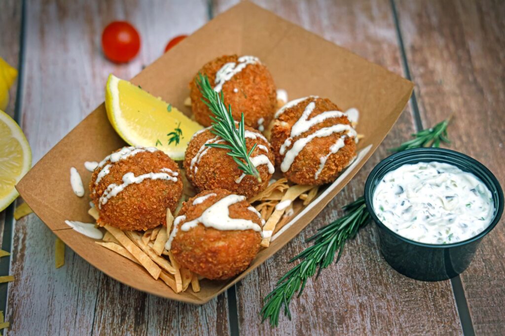 Délicieuses croquettes de crabe croustillantes servies avec une sauce tartare, garnies de romarin et de citron.