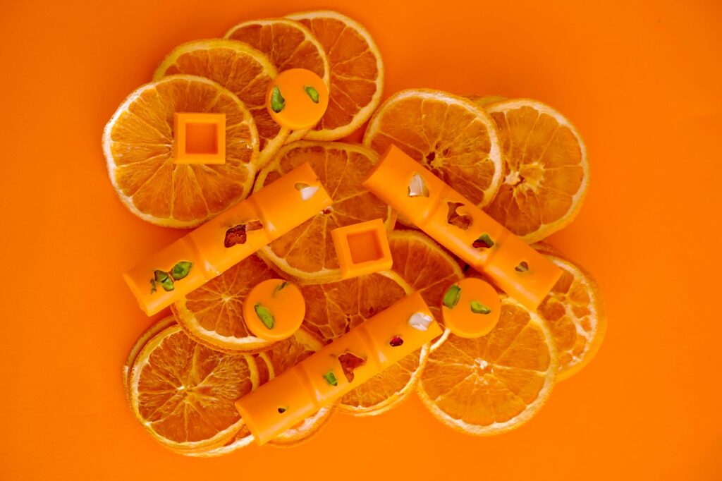 Vue de dessus de tranches d'orange avec des pralinés en chocolat artistiquement disposés sur un fond orange.