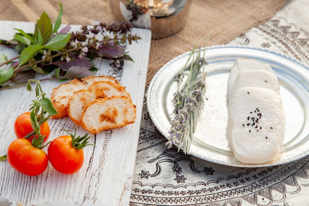 Pain tranché, tomates fraîches et fromage avec des graines de sésame noir dans une présentation rustique.