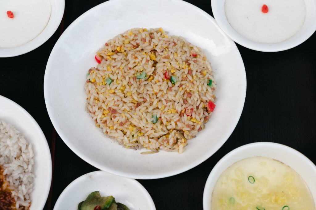 Riz frit asiatique savoureux servi avec plusieurs plats d'accompagnement, capturé en vue de dessus classique.